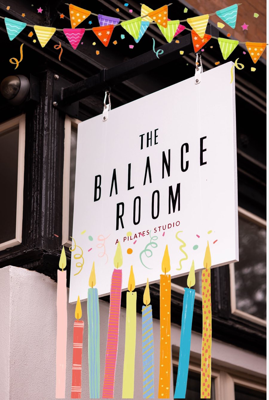 The Balance Room’s hanging street sign under drawn bunting, with birthday candles across the bottom